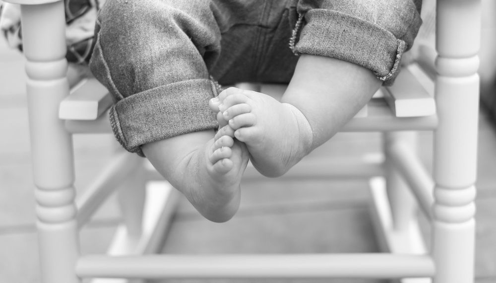 a close up portrait of a baby's feet while sitting in a rocking chair