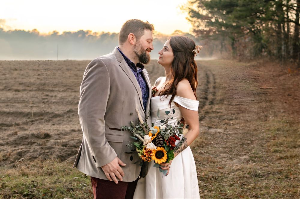 a close up portrait of a bride and groom standing in front of a field