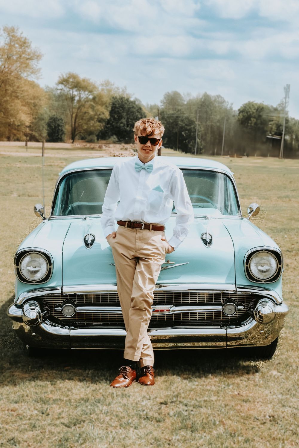 a man dressed up standing in front of a vintage car