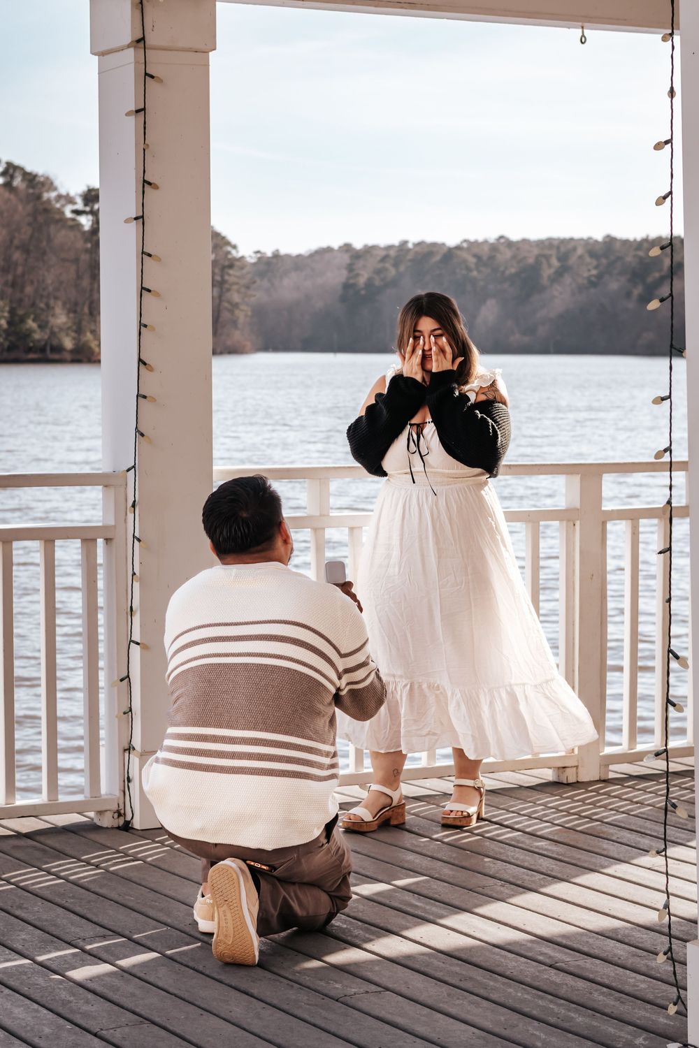 a man proposing to a women in front of a pond