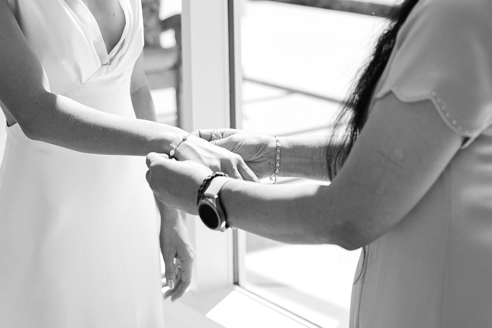 Black and white photograph of hands adjusting a white dress sleeve in front of a window.