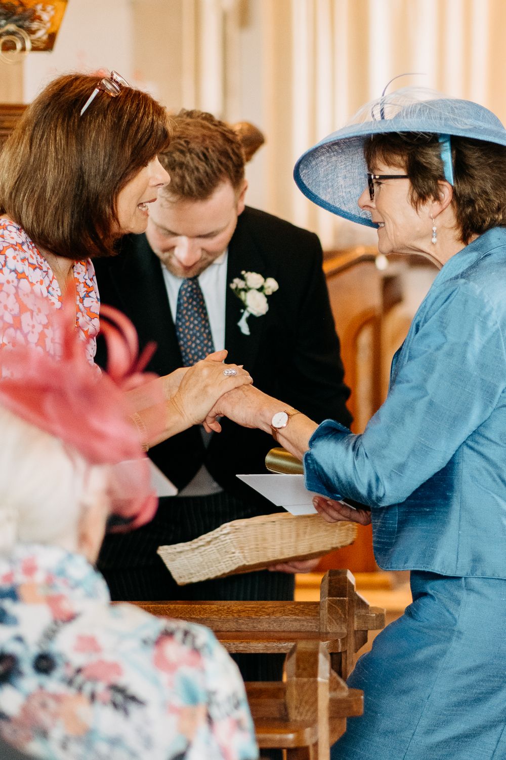 Guests in colorful attire share a joyful moment during a wedding ceremony at an elegant indoor venue.