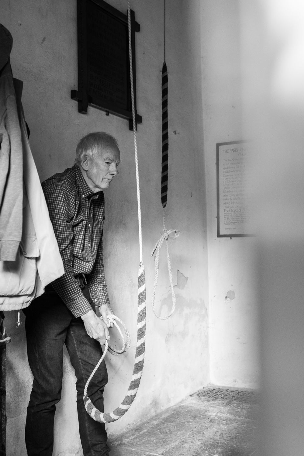 Black and white photo sequence shows a person examining hanging white objects on a wall in alternating frames.