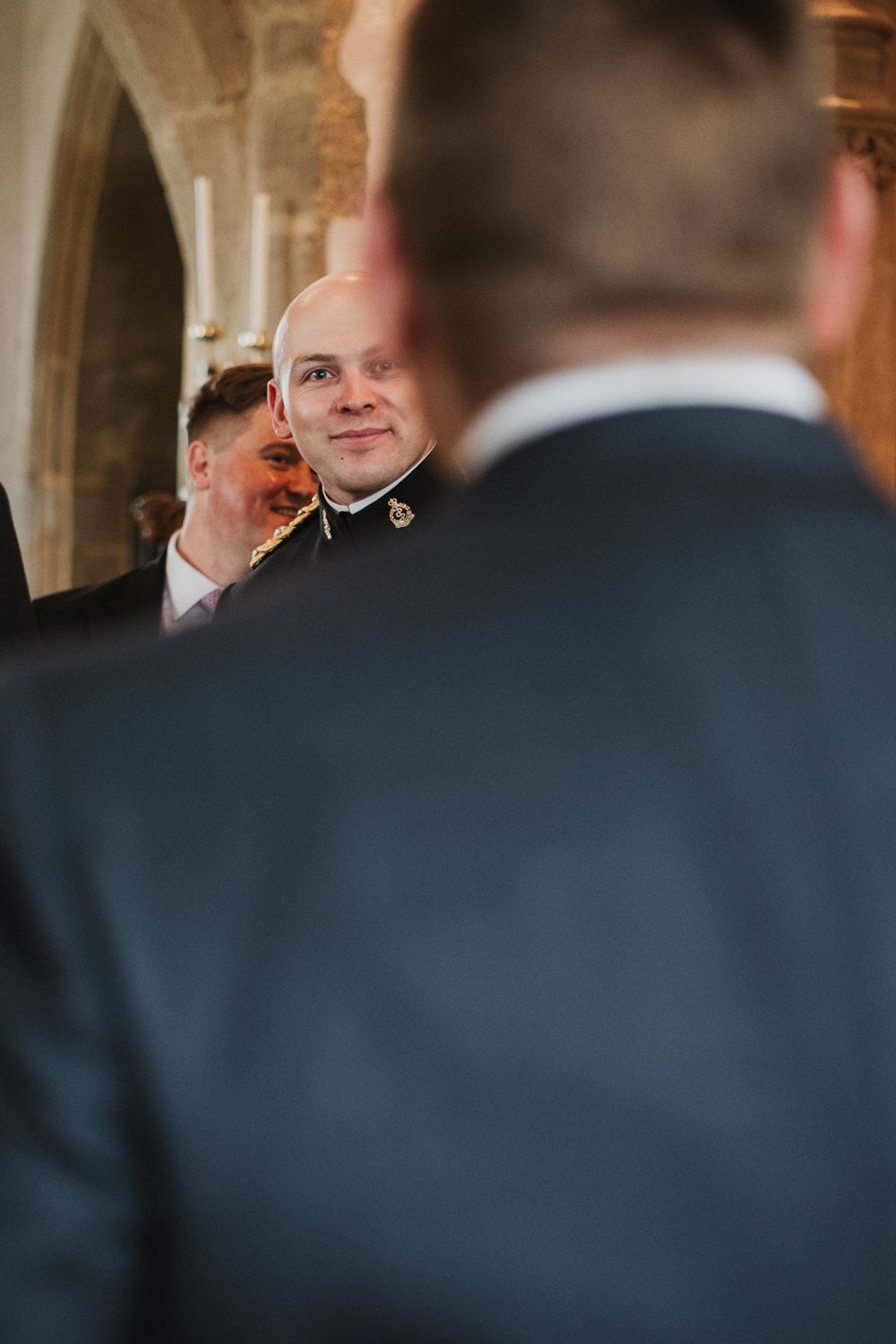 Best man and groomsmen share an emotional moment during wedding ceremony at historic stone church venue.