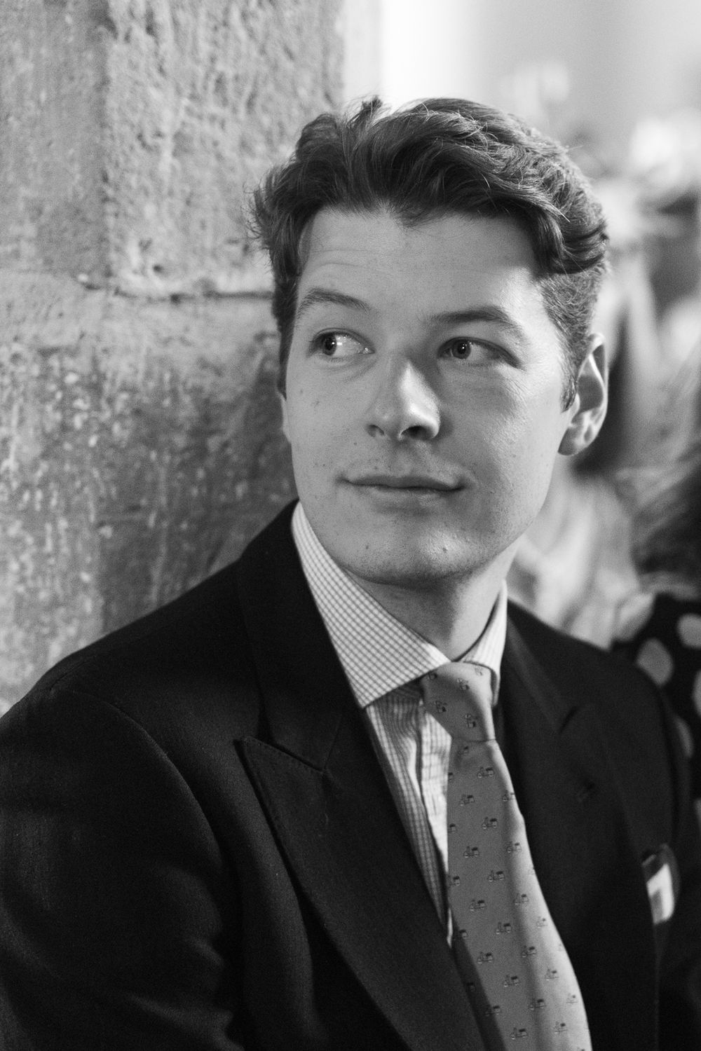 Black and white portrait of a young man in a suit and tie looking thoughtfully to the side.