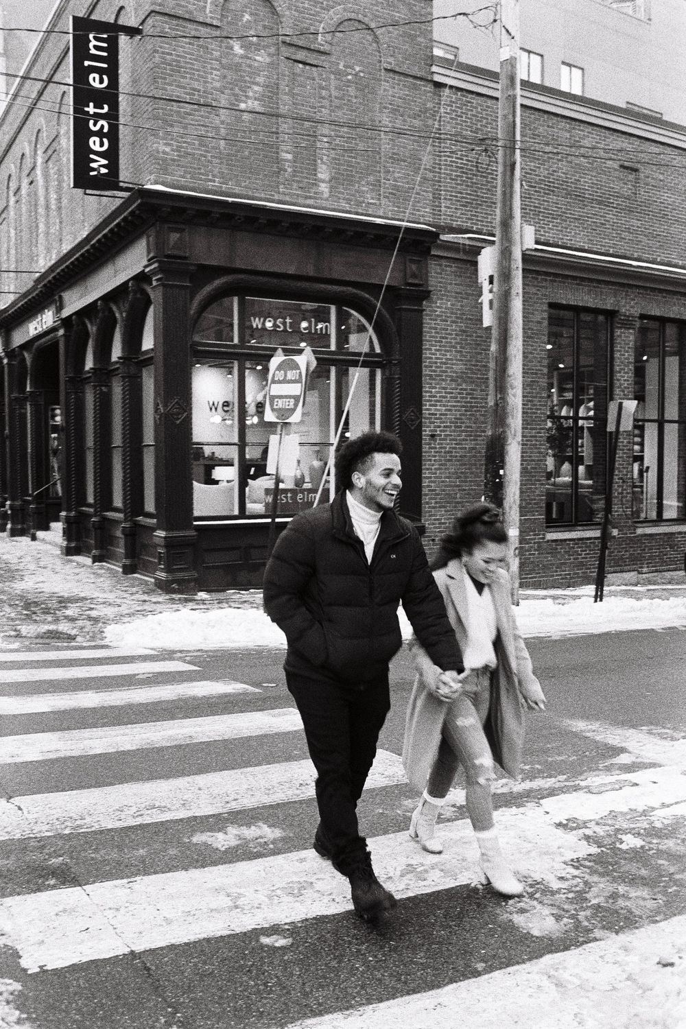 A couple holds hands as they cross the street in downtown Portland, Maine on black and white film.