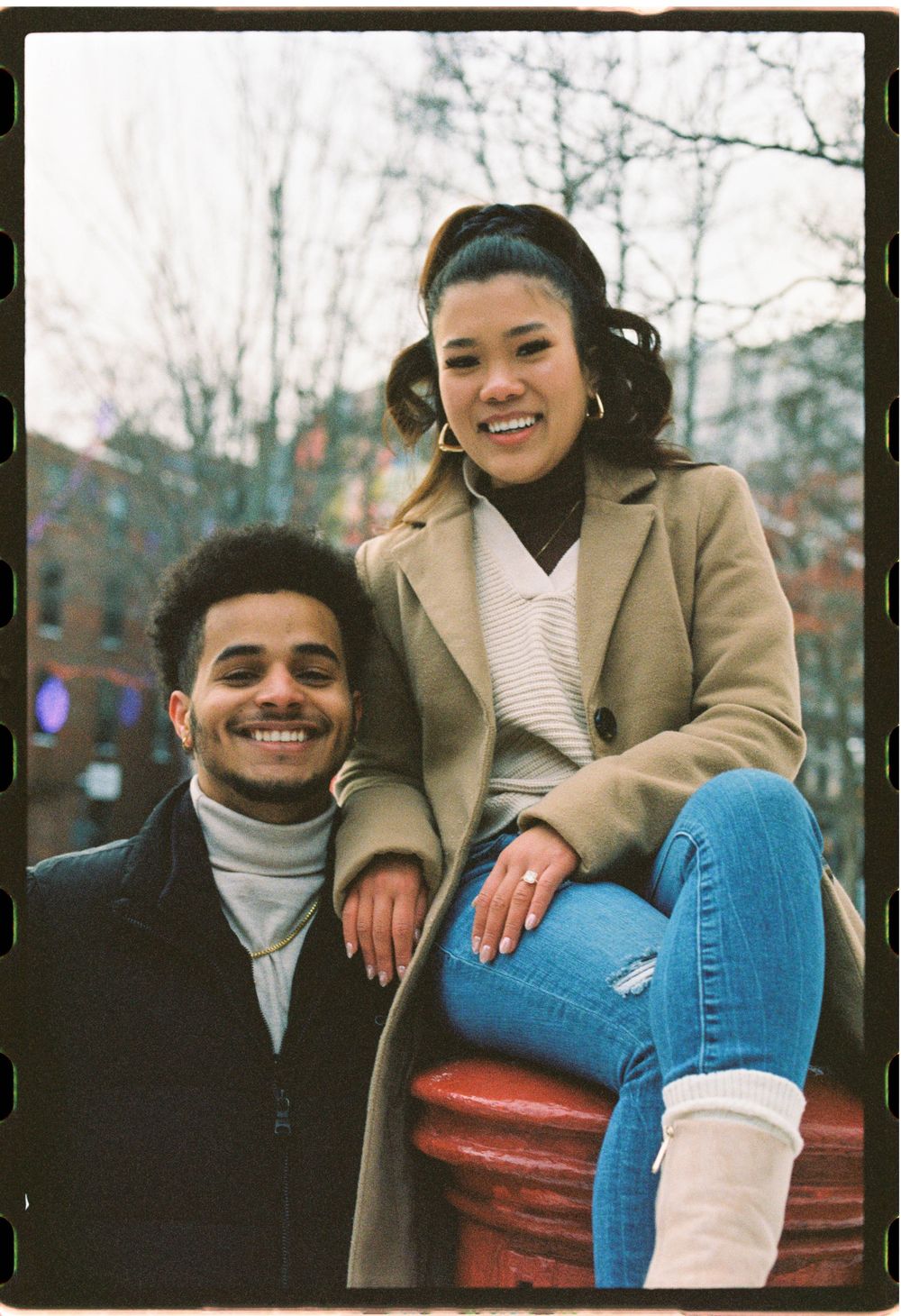 Recently engaged couple poses together smiling in a park in the winter in downtown Portland, Maine.