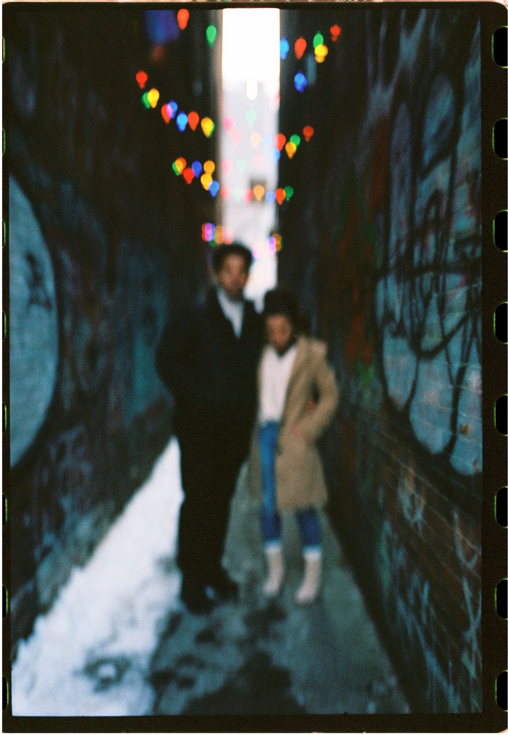 Artful photograph on 35mm film of recently engaged couple laughing together in a quaint alleyway in downtown Portland, Maine.