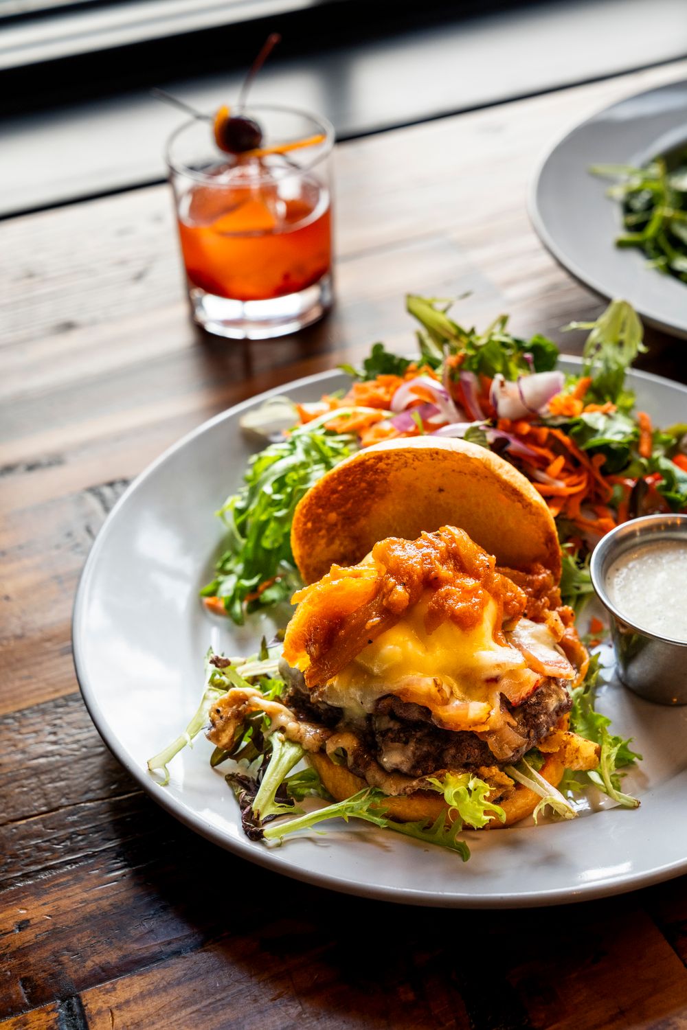 Gourmet taco with melted cheese and salad served alongside cocktail.