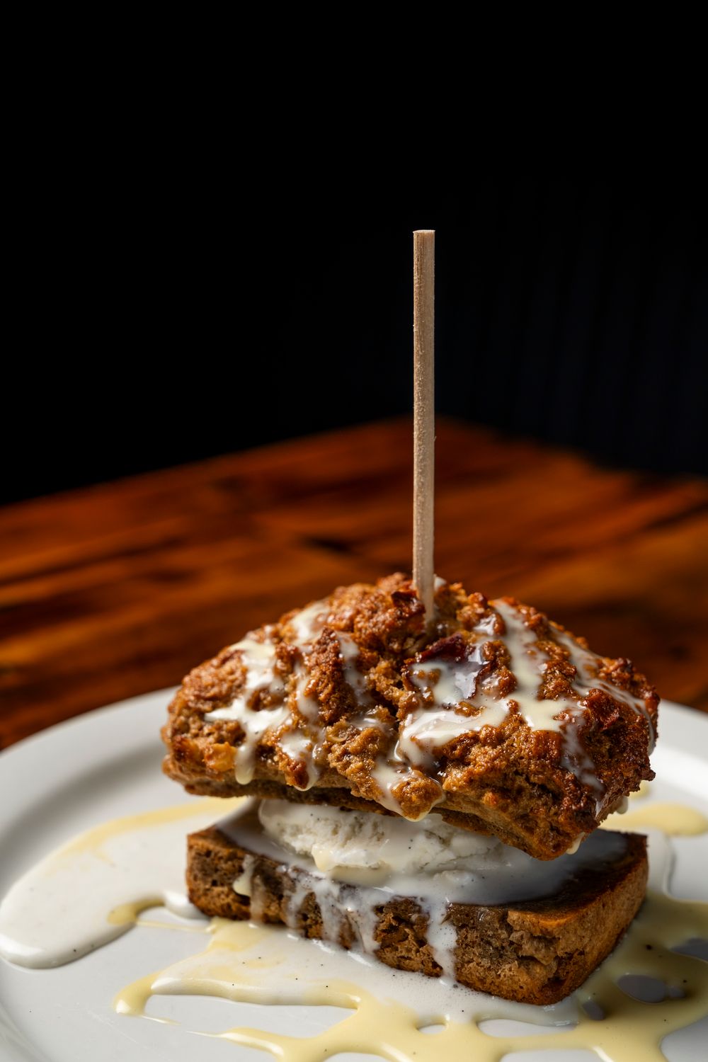 Close-up of a decadent dessert with cream sauce and chocolate crumbles on a white plate.