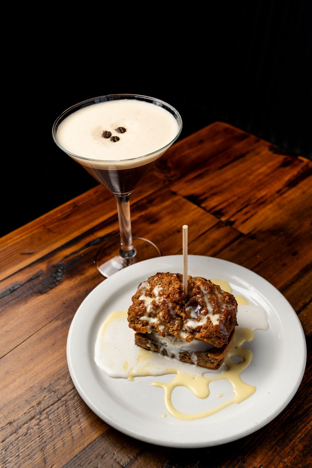 Elegant cocktail and plated dessert presentation on a rustic wooden table.