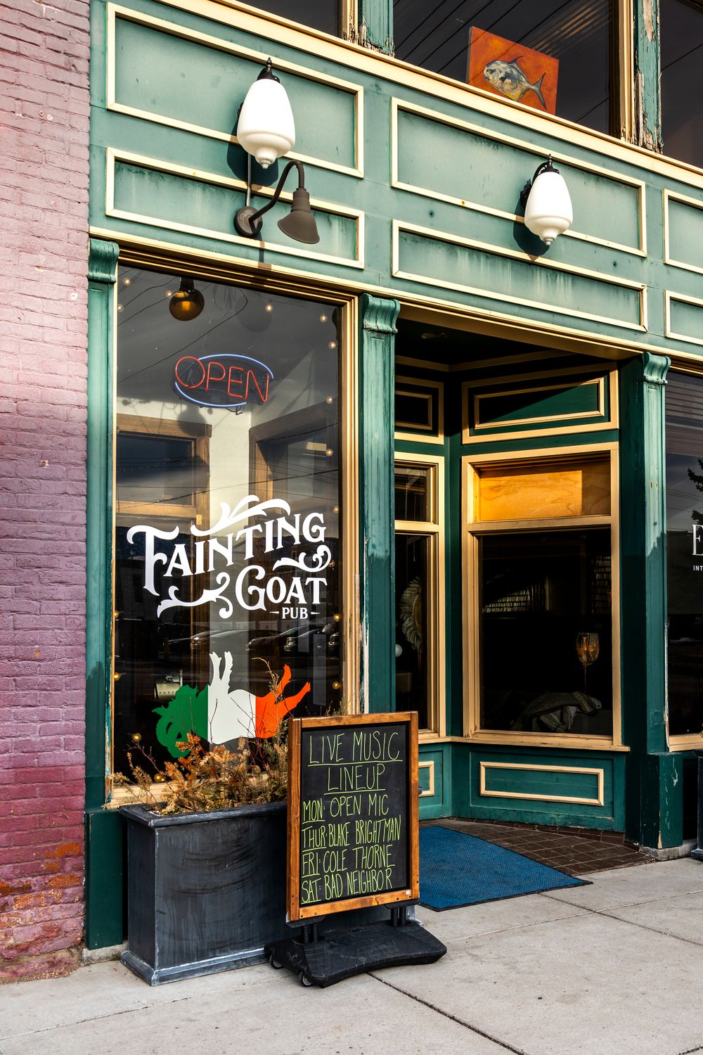 Storefront of Fainting Goat with green trim and pink brick exterior.