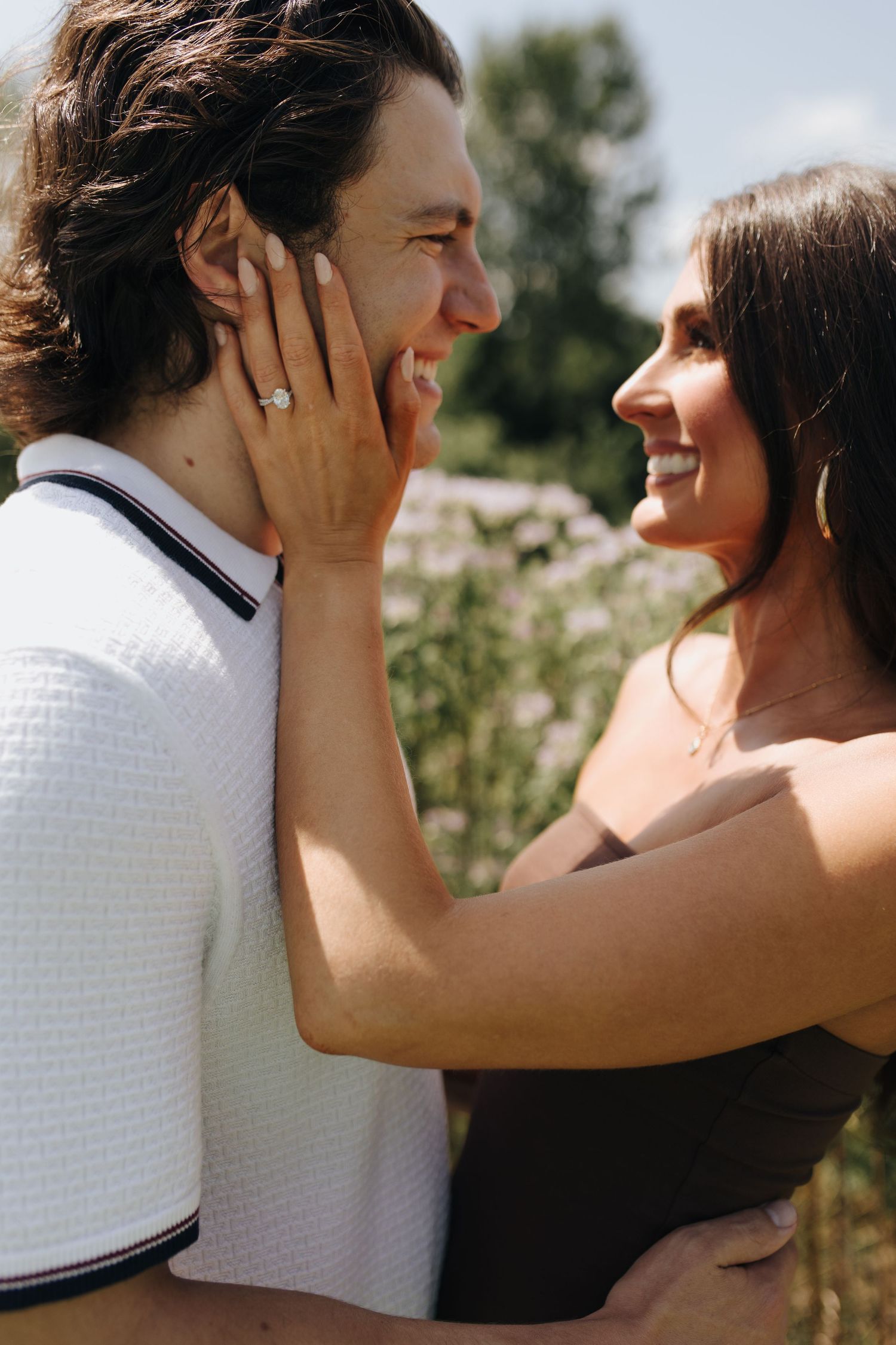 Happy couple smiling and embracing after proposal in Columbus, Ohio, with a close-up on engagement ring.