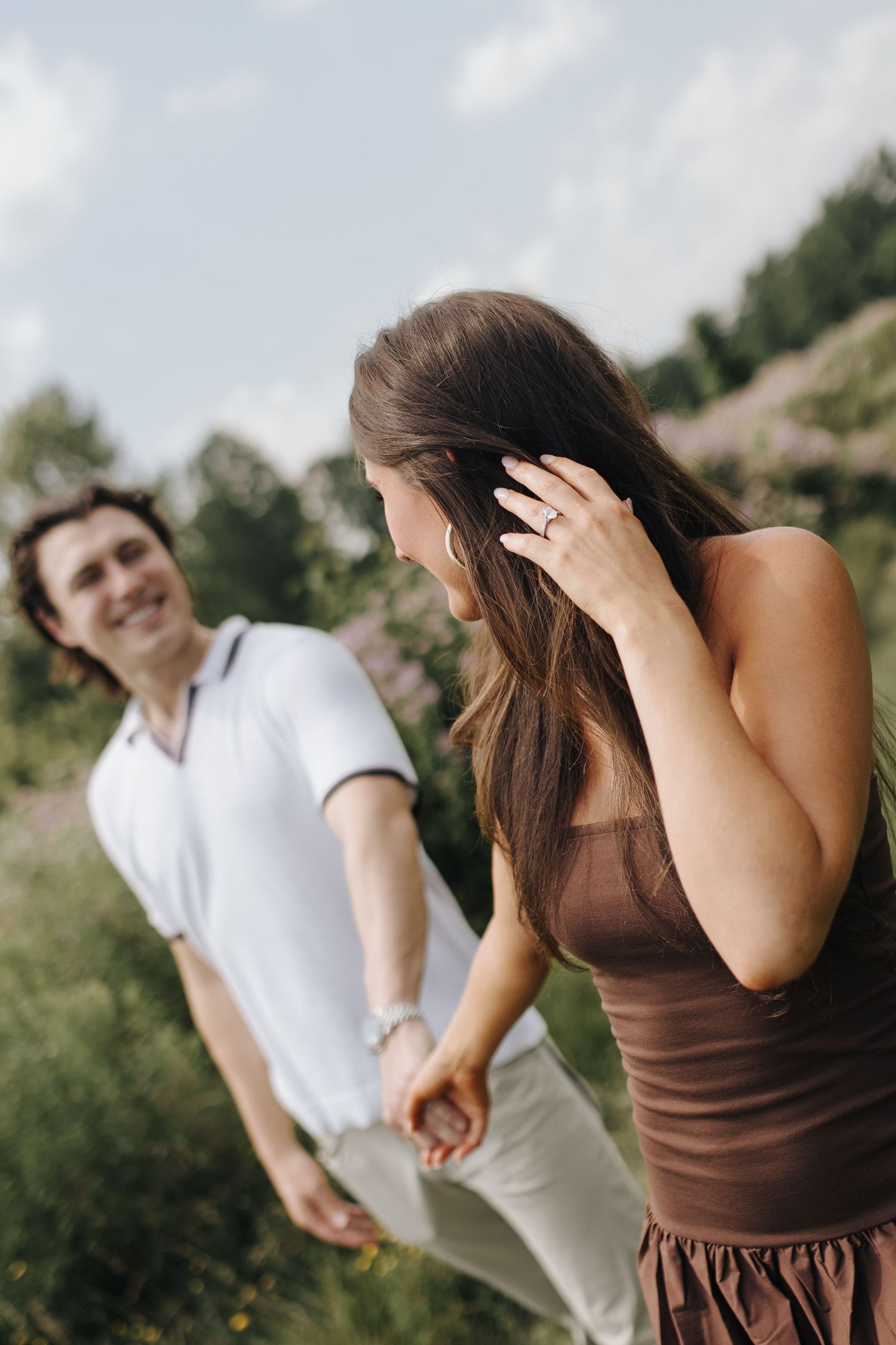 Newly engaged bride-to-be showing off her engagement ring while gazing adoringly at fiancé.