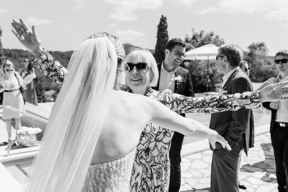 Ein freudiger Moment während der Gratulation an einer Hochzeit. Die Schwiegermutter gratuliert der Braut mit offenen Armen am Pool der Finca
