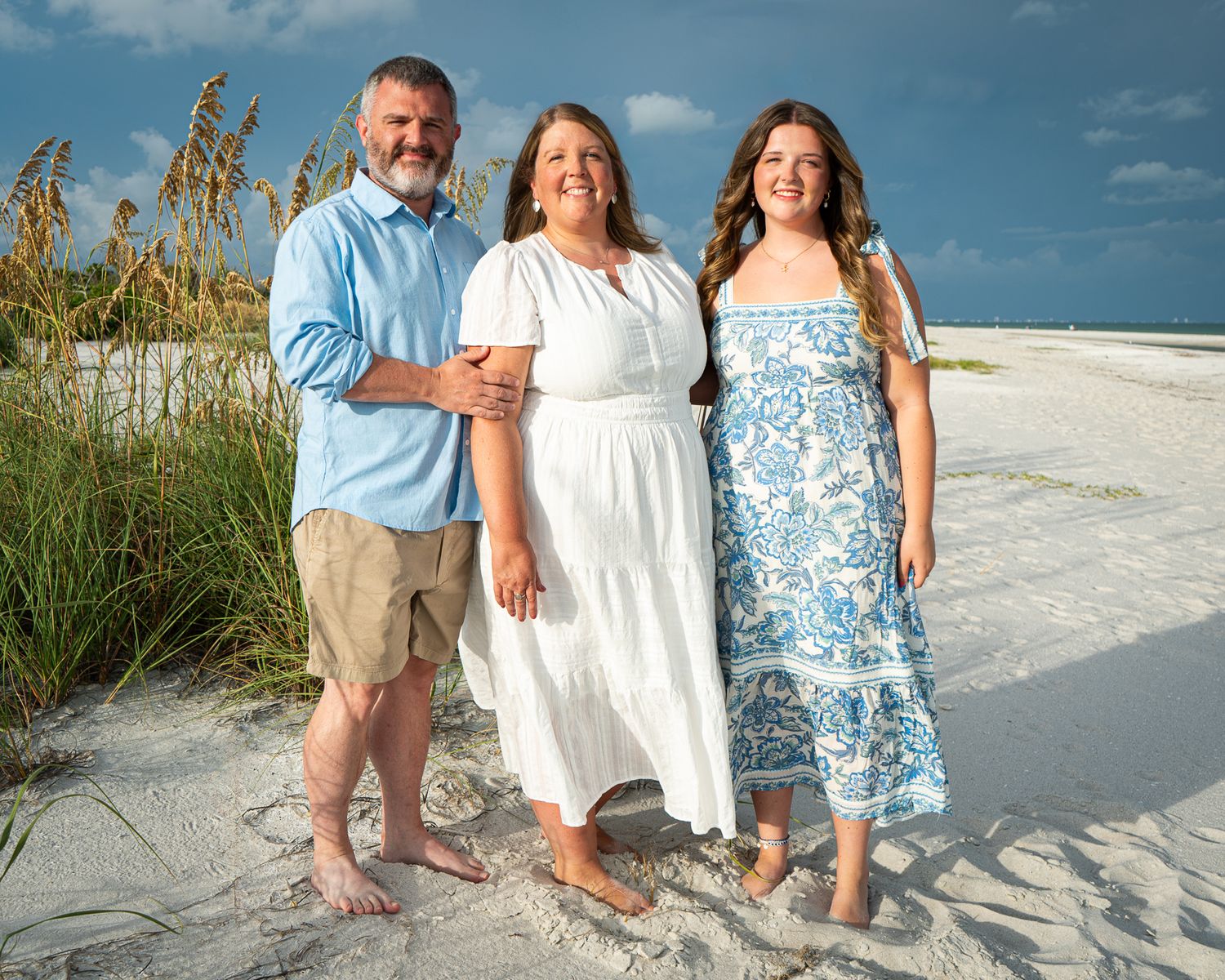 A family portrait session on a white sandy beach at sunset.