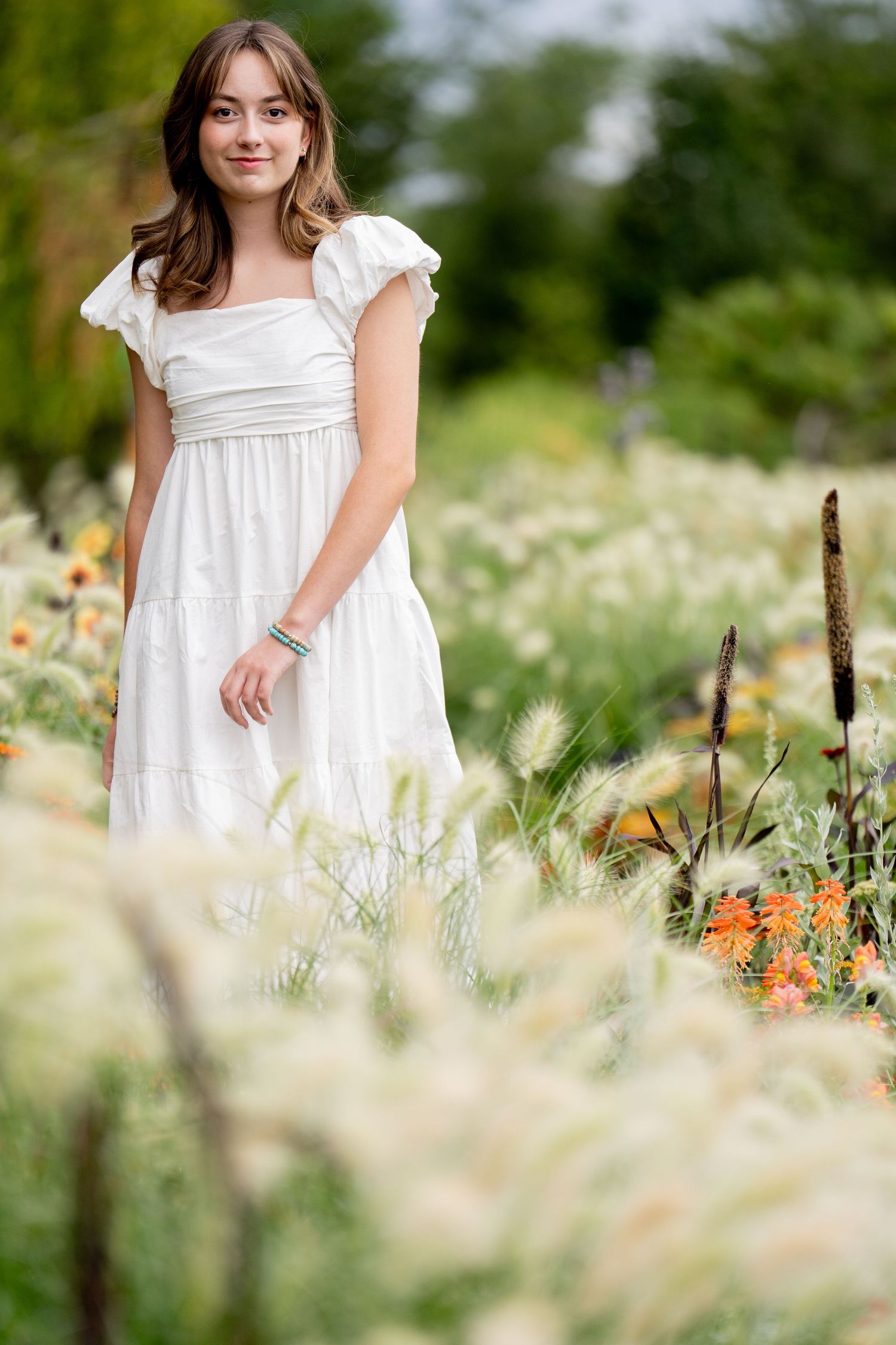 A dreamy summer garden scene with orange flowers and tall ornamental grasses.