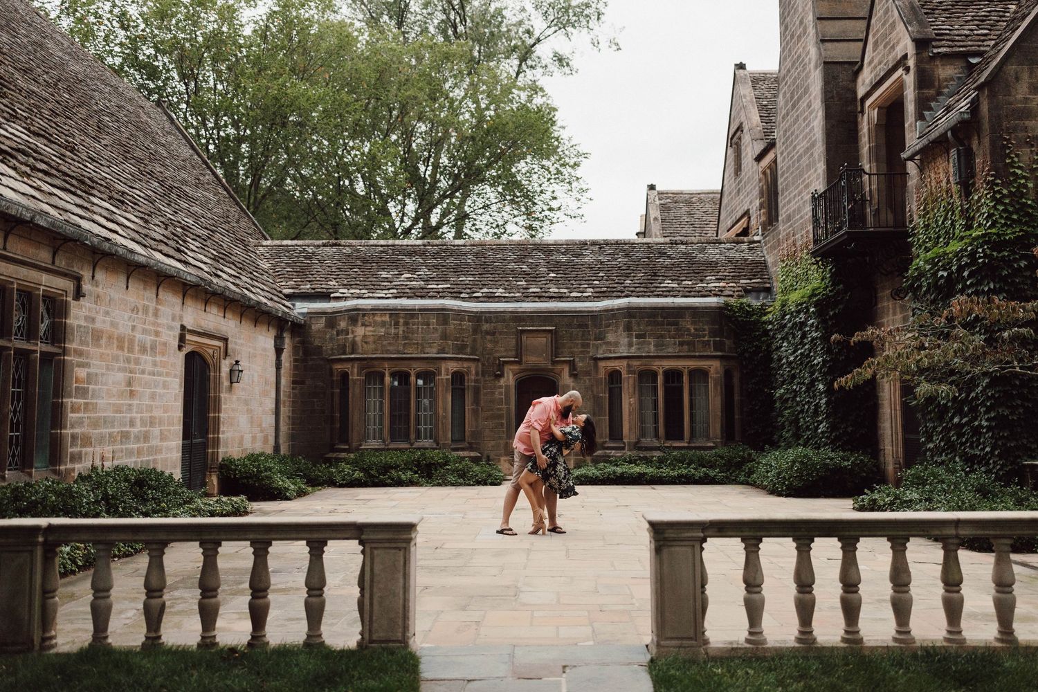 A romantic moment in a historic courtyard with stone balustrades and ivy-covered walls.