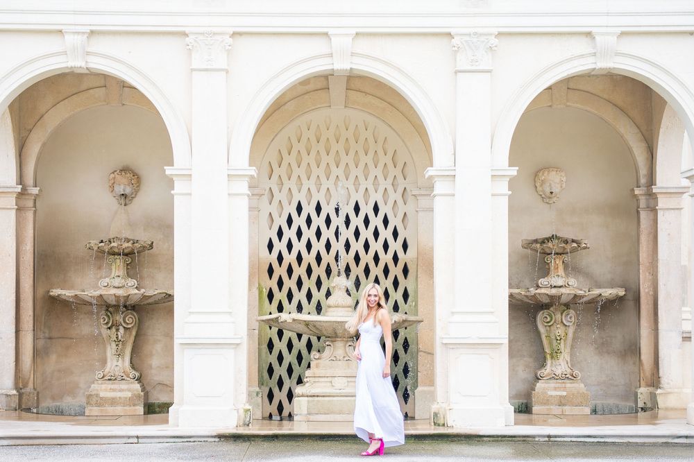 Elegant white archways with ornate fountains frame a geometric latticed doorway in a classic architectural setting.