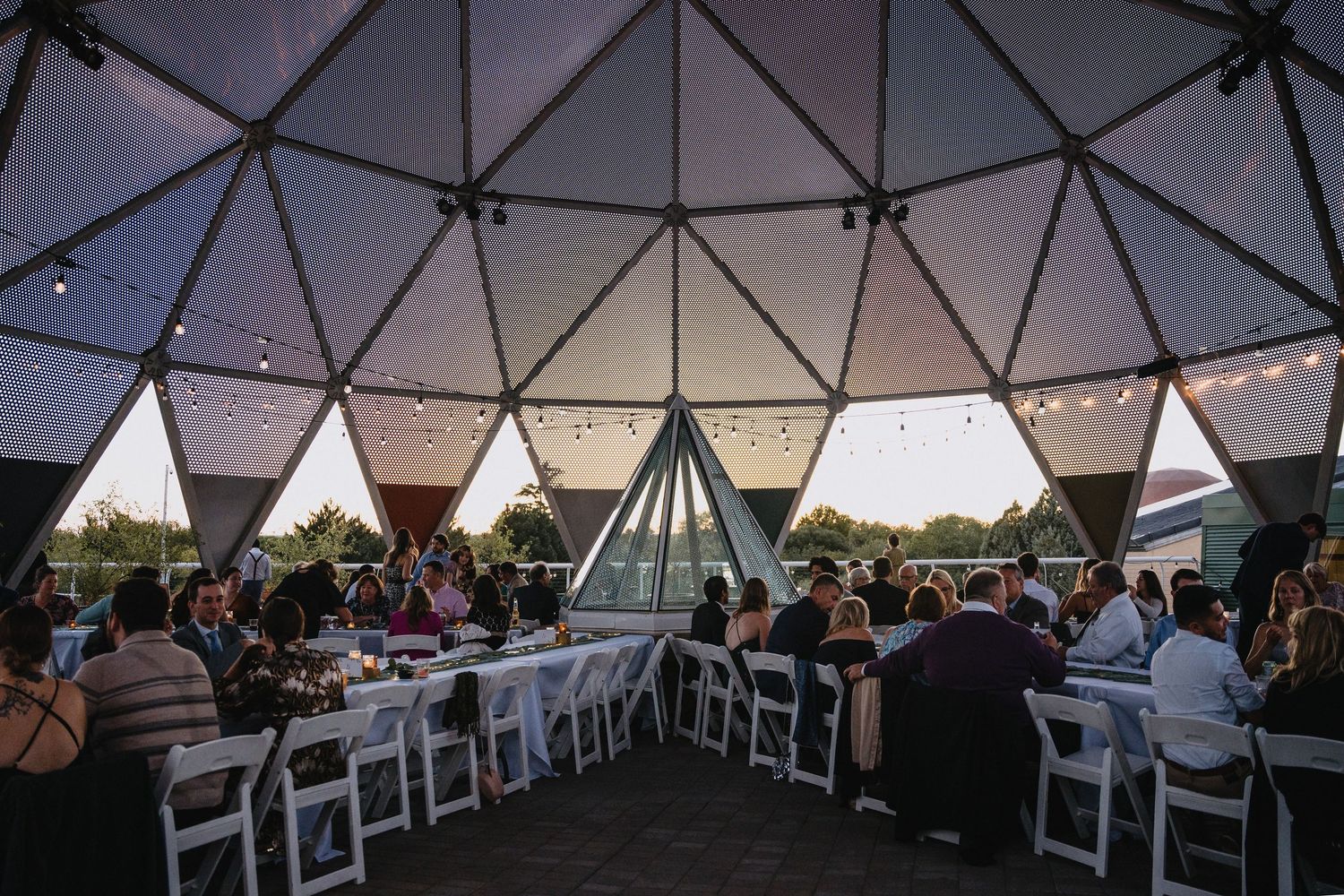Wedding reception dinner inside a geometric dome venue at twilight with string lights.cinematic wedding photographer new mexico
