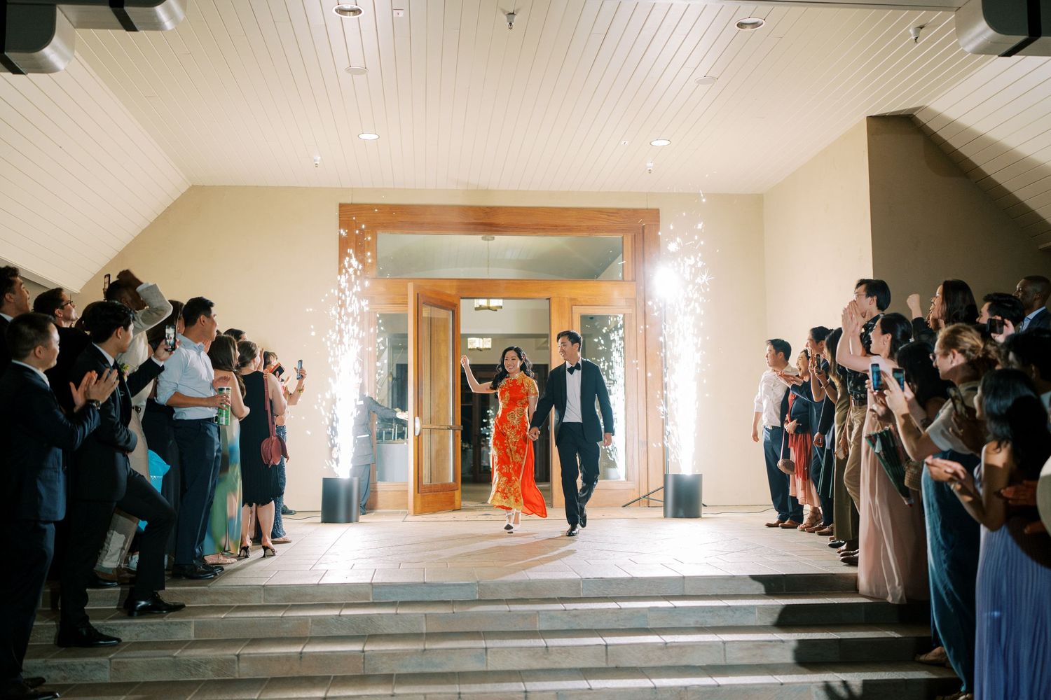 Wedding exit celebration with sparklers lining hallway as guests create magical sendoff moment.