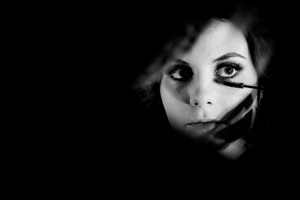 Dramatic black and white portraits show eyes and partial faces emerging from darkness in an artistic composition.