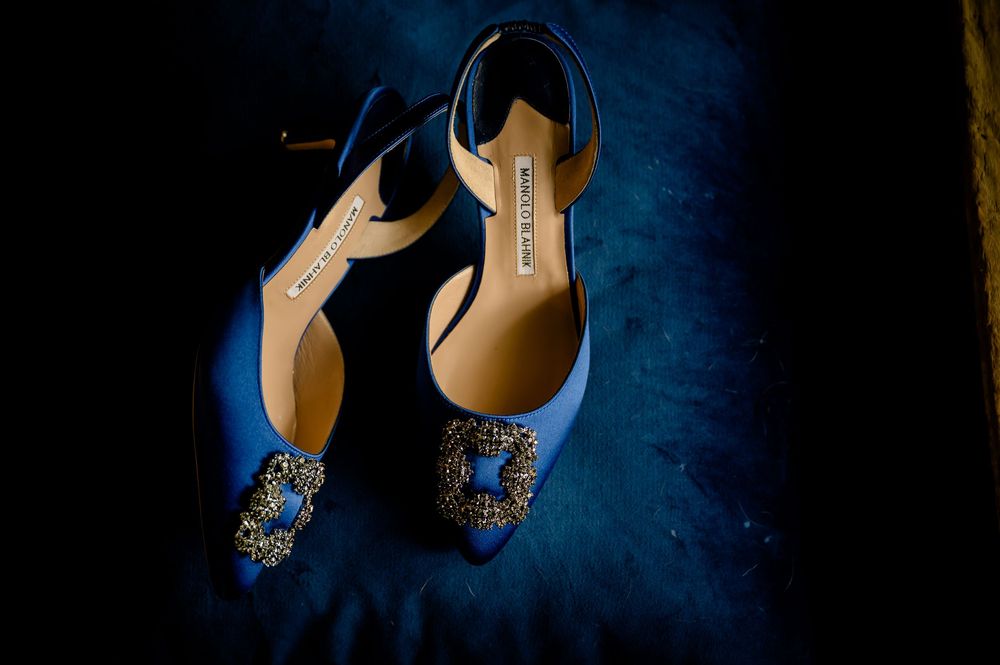 Elegant blue bridal shoes with ornate crystal embellishments photographed on dark background.