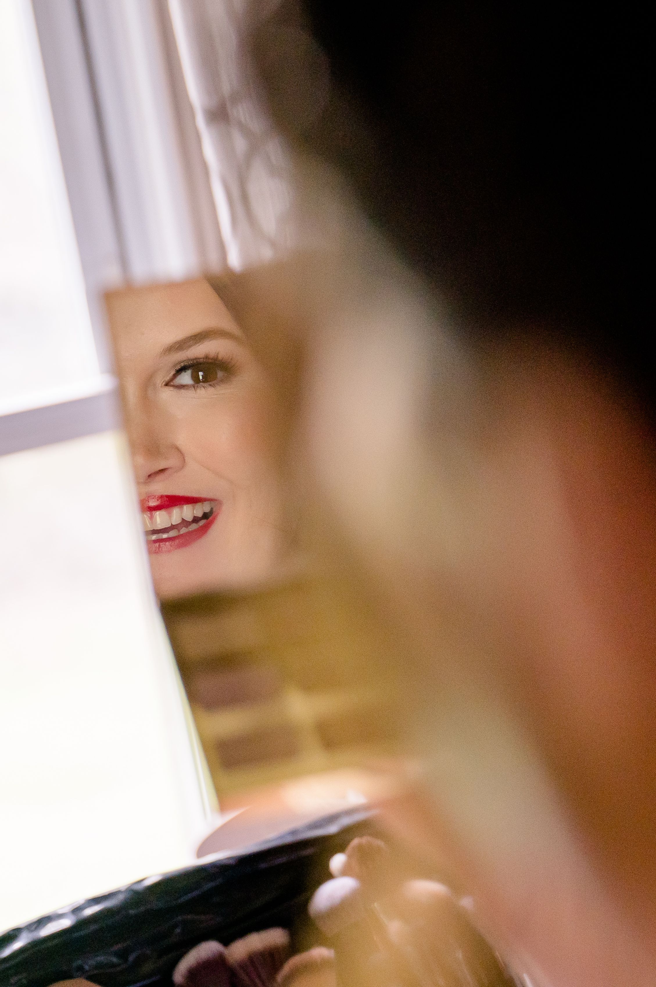 Close up artistic shot showing vibrant red lipstick in soft window light.