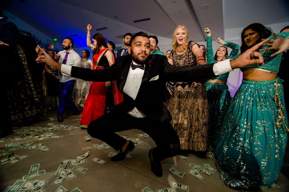 People dancing energetically at a formal event with guests in elegant dresses and tuxedos on a confetti-covered dance floor.