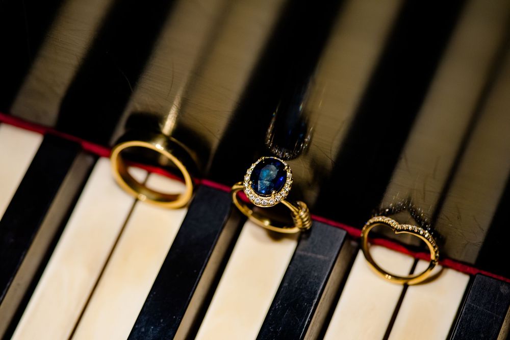Close-up aerial view of piano keys and golden wedding rings arranged on the black and white keyboard.