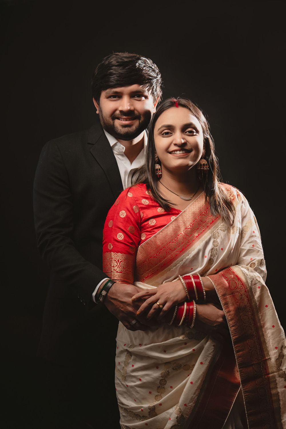 A romantic photoshoot series showing a couple in traditional Indian attire embracing against a dark background.