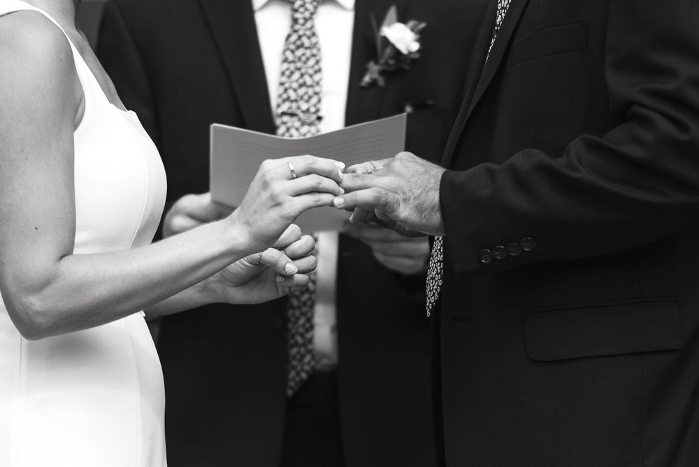 A bride and groom stand at the altar during their wedding ceremony while guests look on.