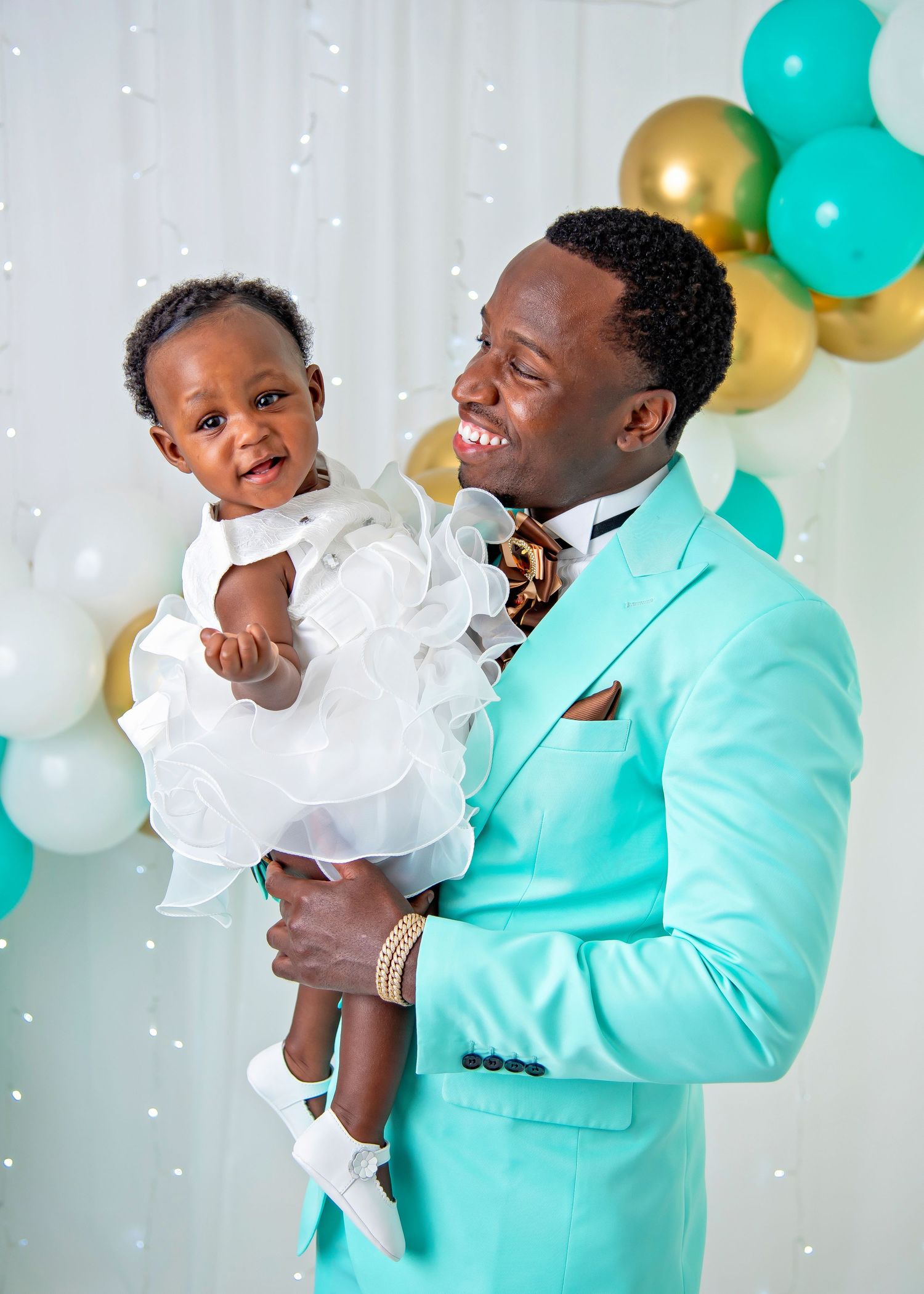 Joyful family moment captured in turquoise and white themed photoshoot with balloons in the background.