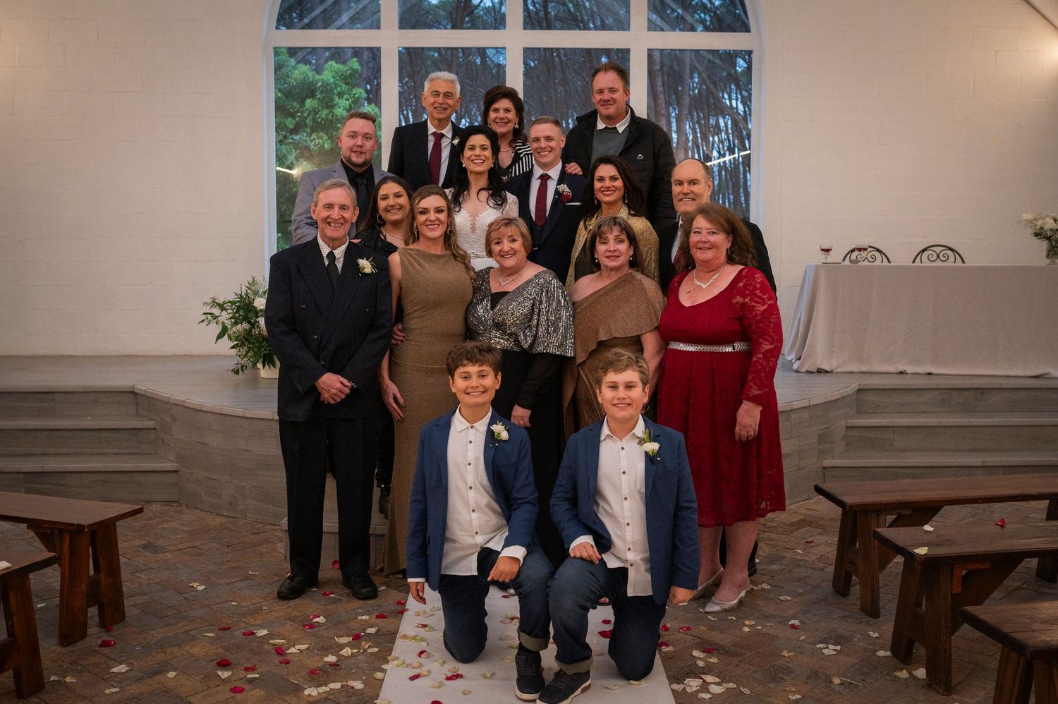 Formal group portrait of elegantly dressed people posing together at a church ceremony venue.
