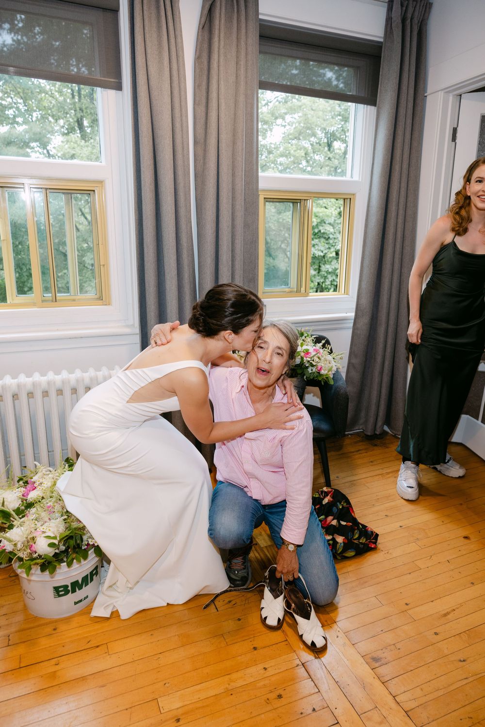 An emotional moment shared between people in a bright room with wooden floors and floral decorations.