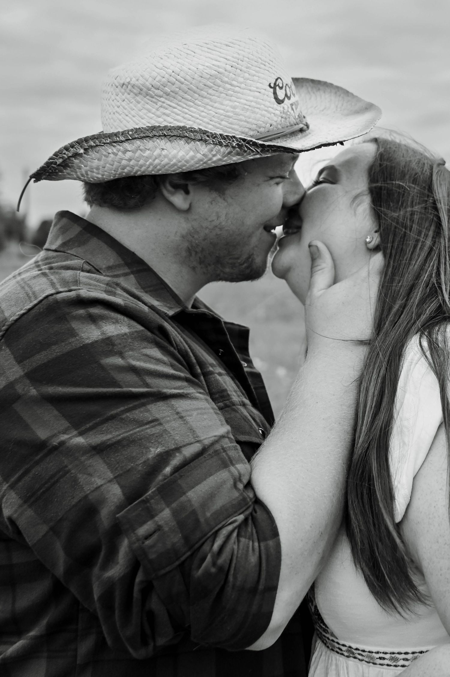 Intimate black and white portrait of a romantic couple sharing a tender moment outdoors.