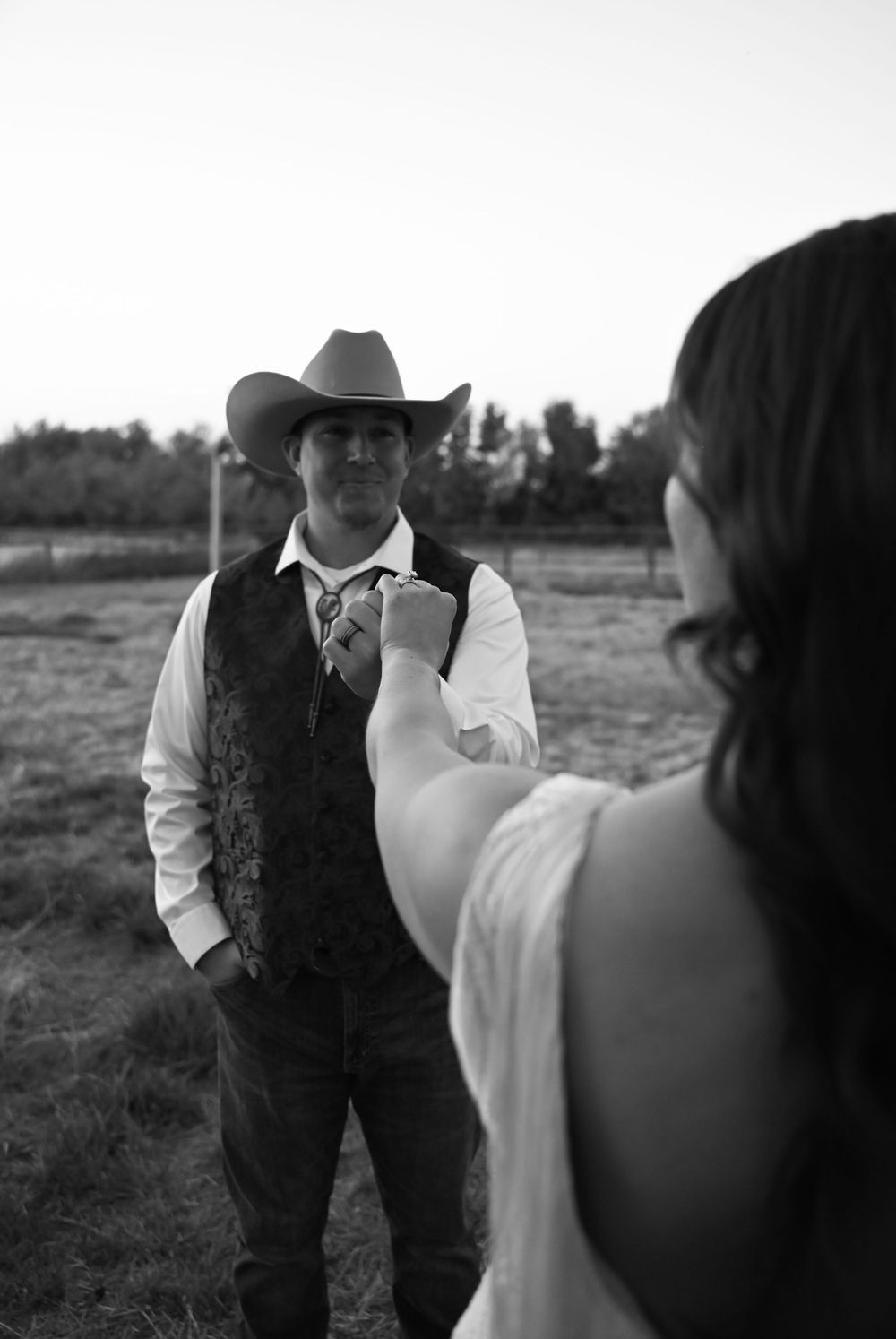 Black and white portrait of a western-styled couple during their countryside wedding.