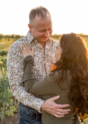 A romantic sunset portrait of a couple embracing in a field with golden light.