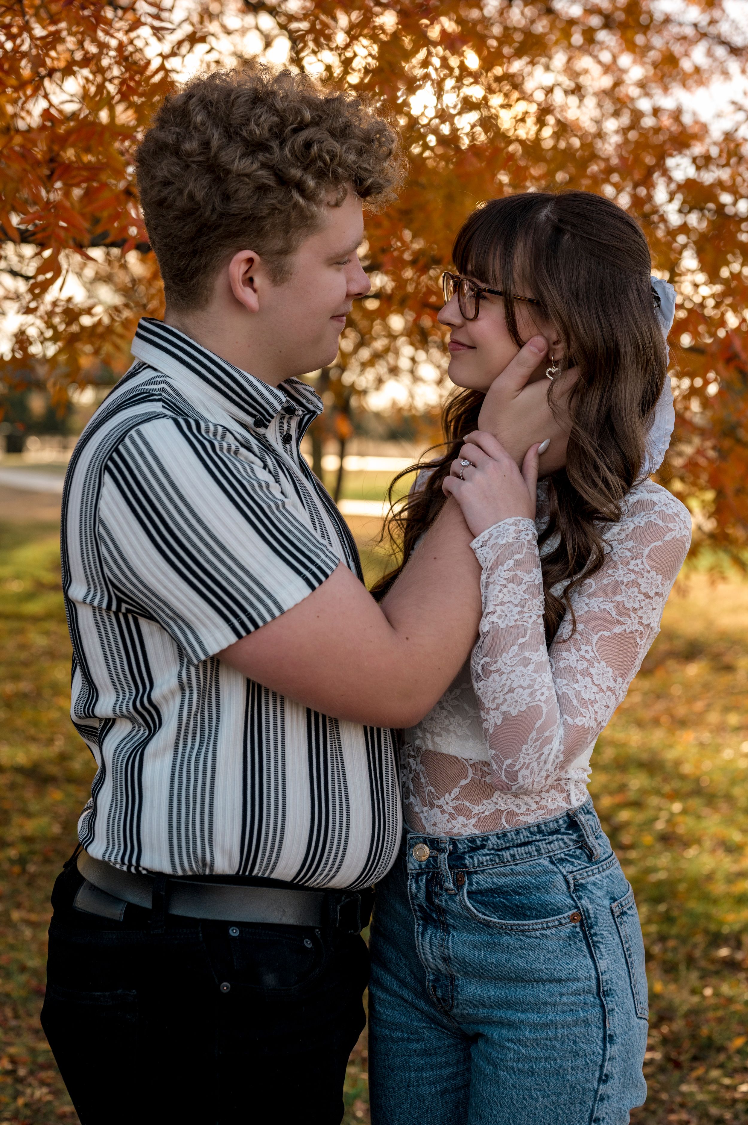 Intimate moment between couple in vintage-inspired outfits under autumn trees.