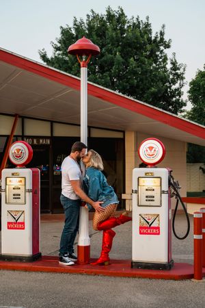 Romantic sequence of couple at vintage retro-styled gas pumps during an evening engagement photo session.