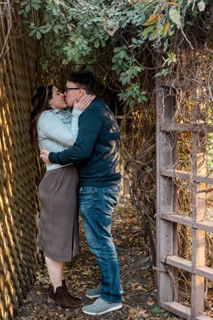 Couple sharing romantic moment in garden setting surrounded by foliage.