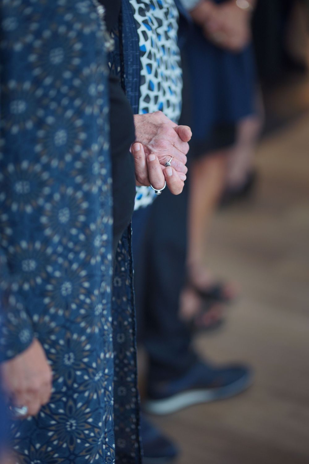 Close-up of hands holding together in a blue patterned dress.