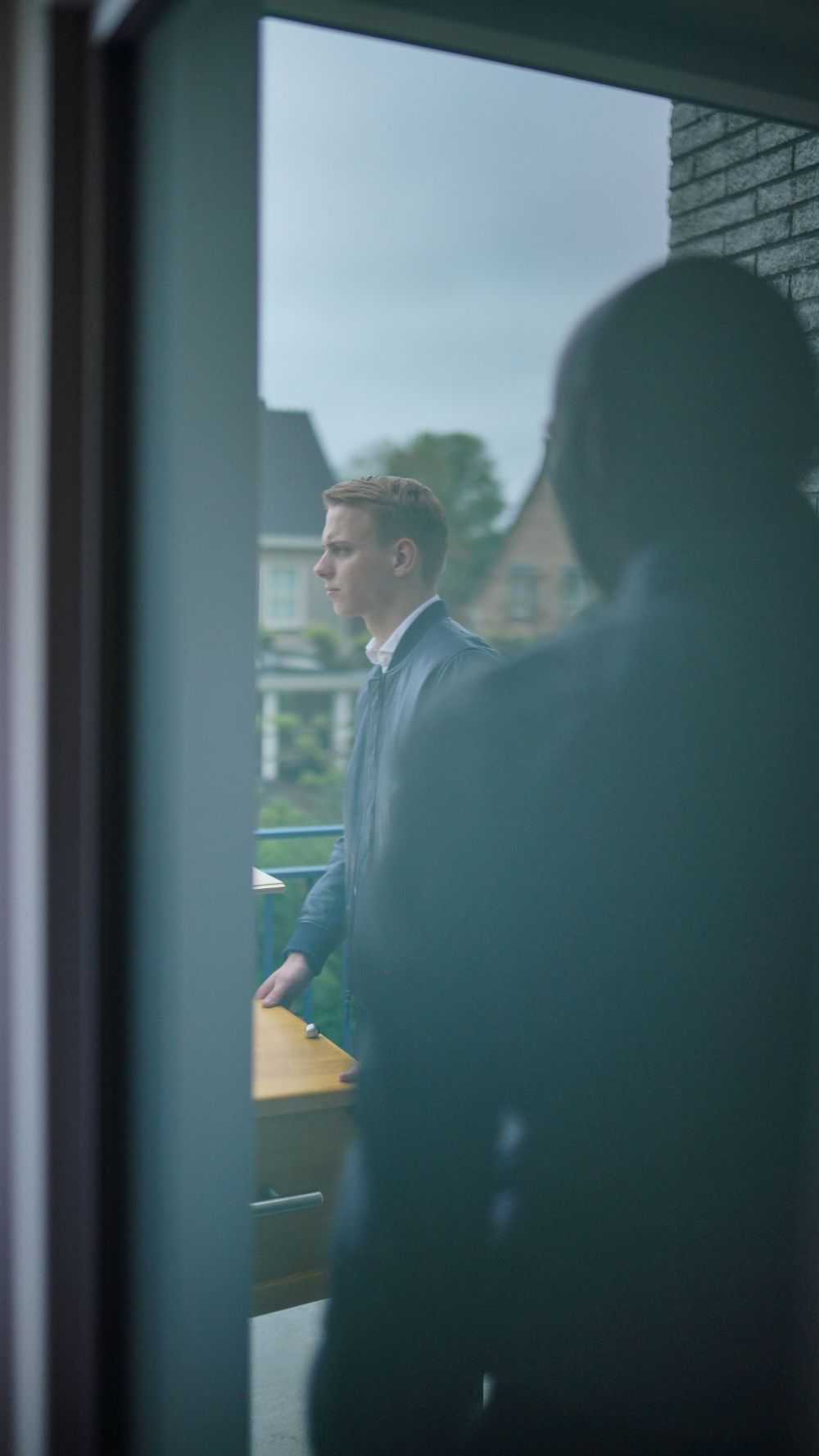 View through window showing formal gathering in soft natural light.