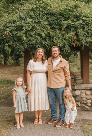 Family group poses together on stone path with green trees in background.