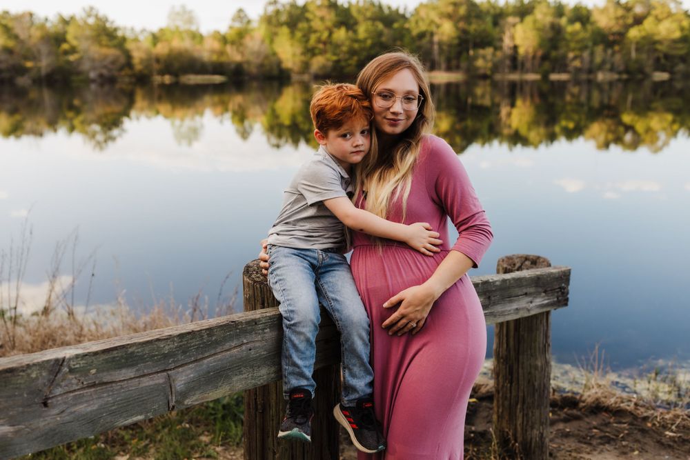 Heartwarming outdoor portrait by lake with parent and child embracing on wooden dock.