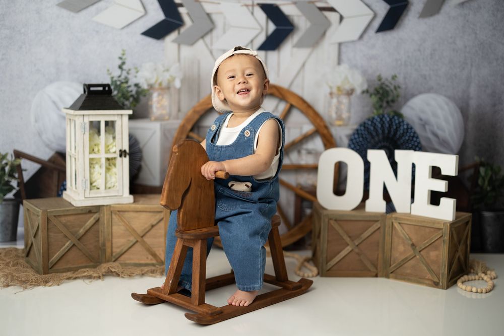 A series of milestone photos showing a baby's first year growth progression in matching blue outfits with number signs.