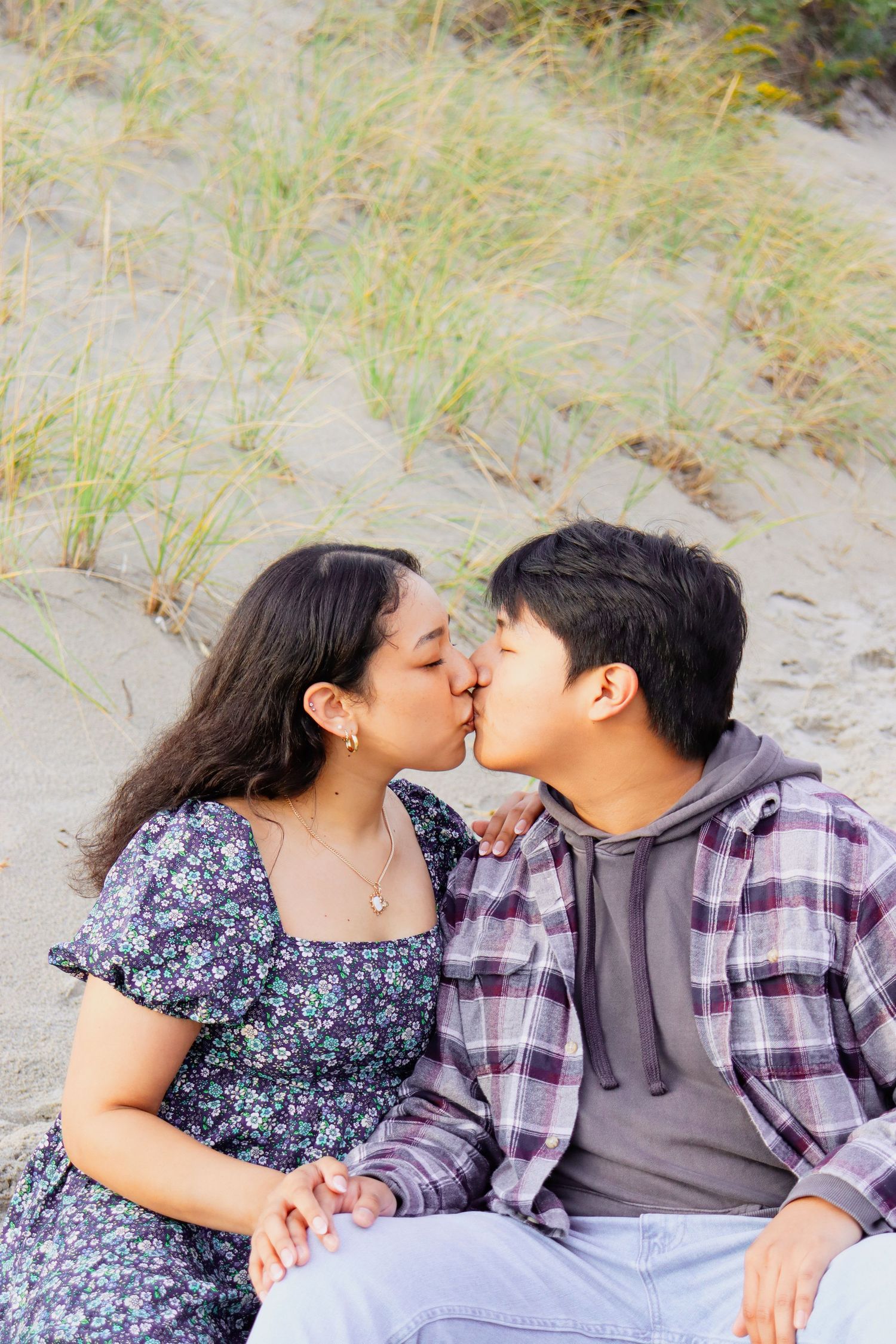Romantic couple sharing an intimate moment on sandy beach dunes.