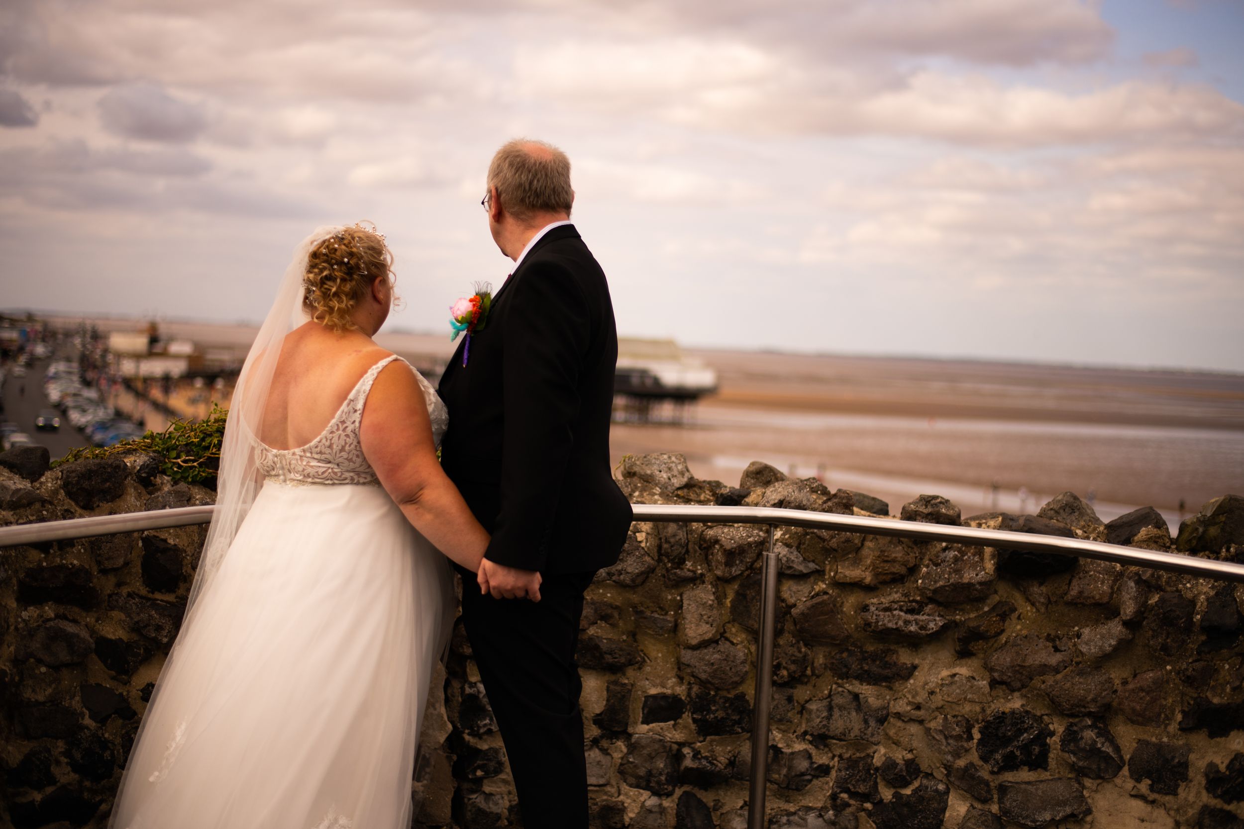 A couple shares an intimate moment overlooking a coastal view from a stone terrace.