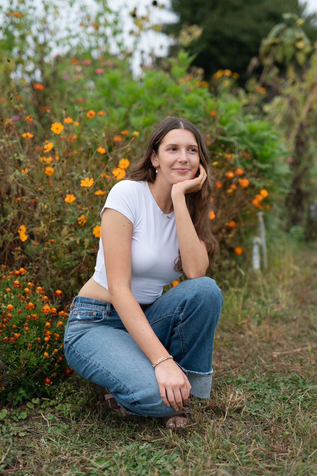 Thoughtful outdoor portrait pose in casual attire among orange wildflowers.