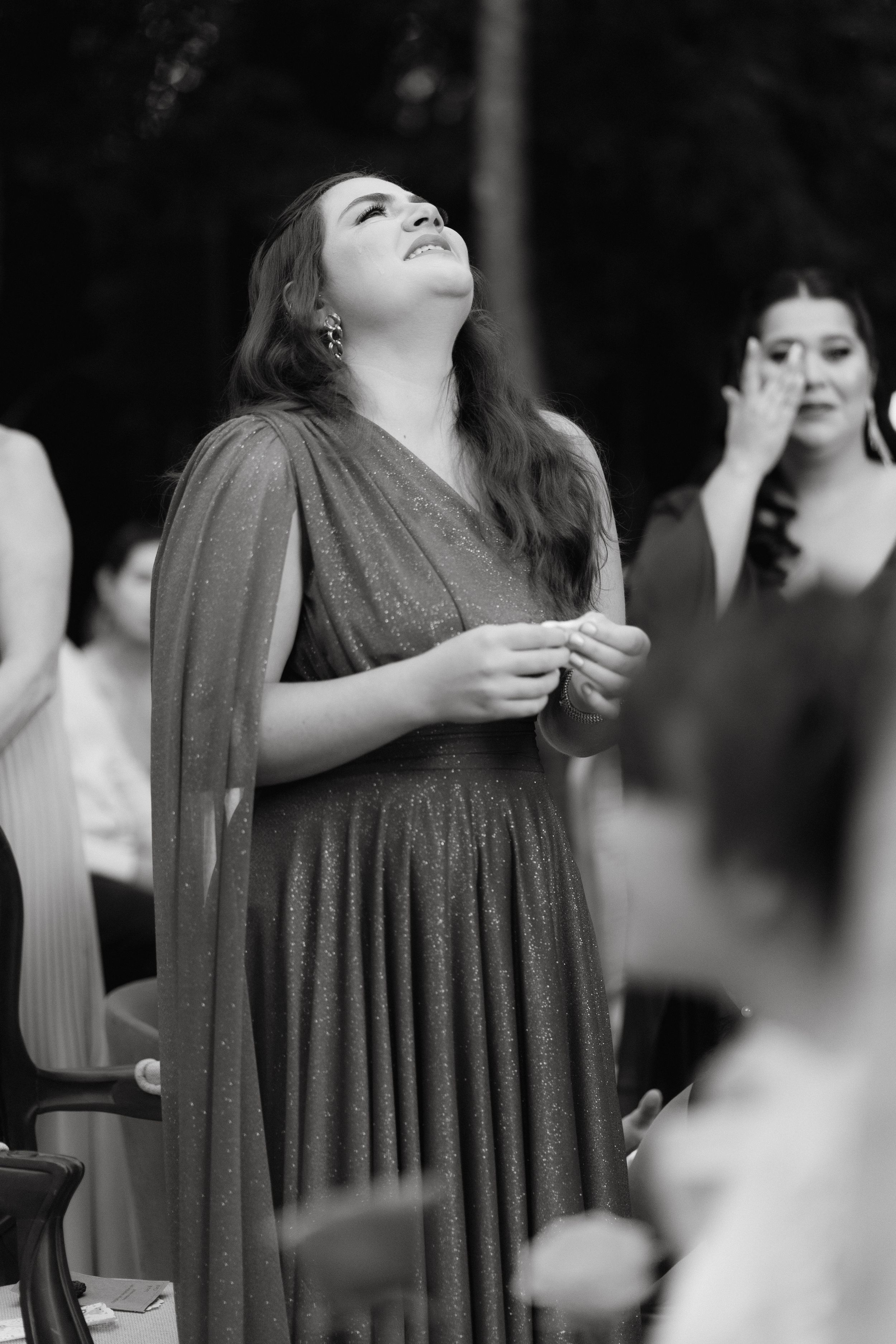 Candid black and white photo of guests showing genuine emotion during a wedding ceremony.